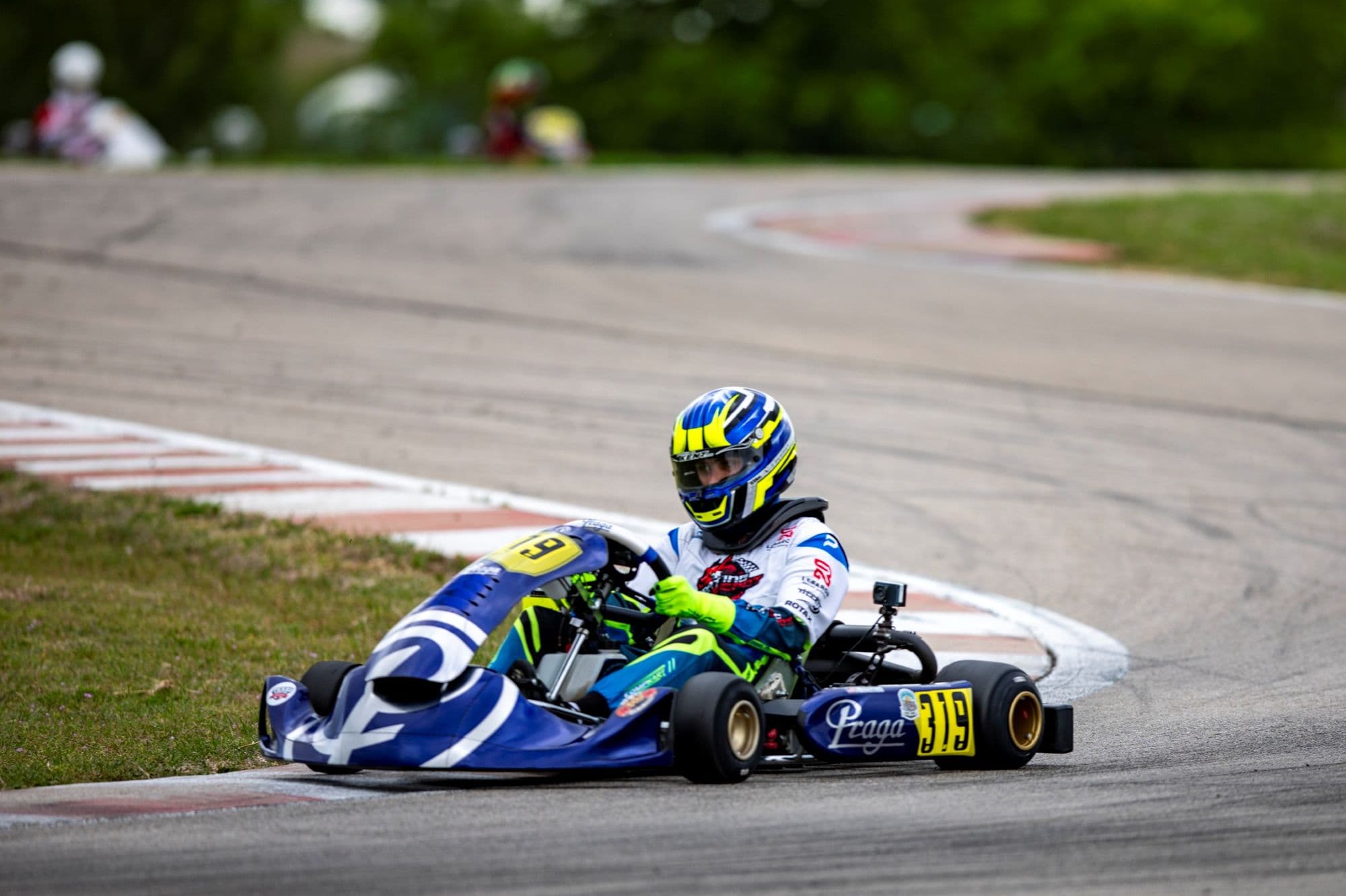 A blue kart with a yellow helmet slides through a corner at KartMoto.