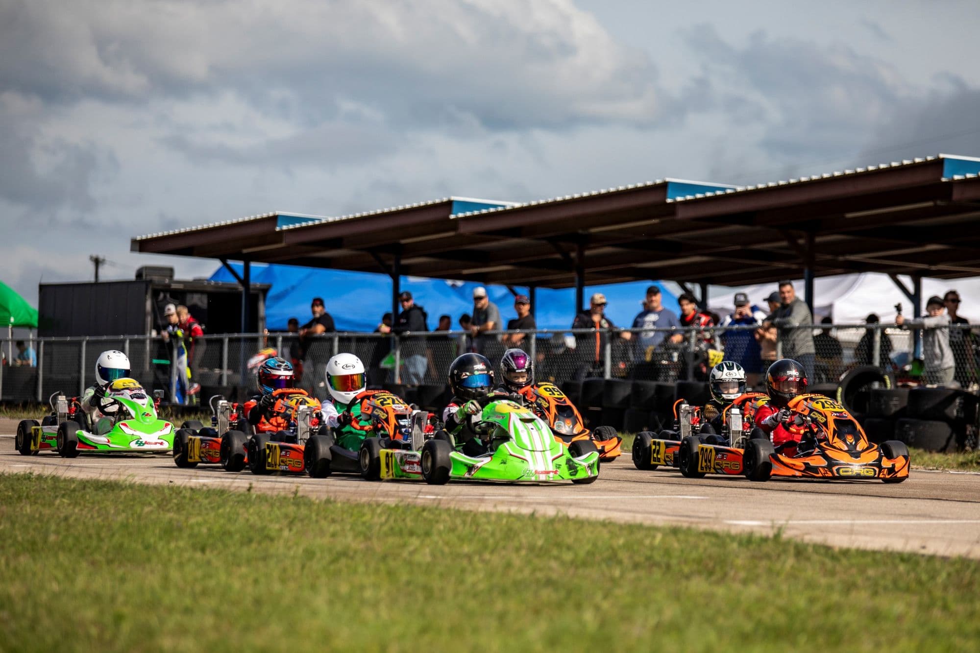 Green karts lined up on the grid beside the pavilion at KartMoto.