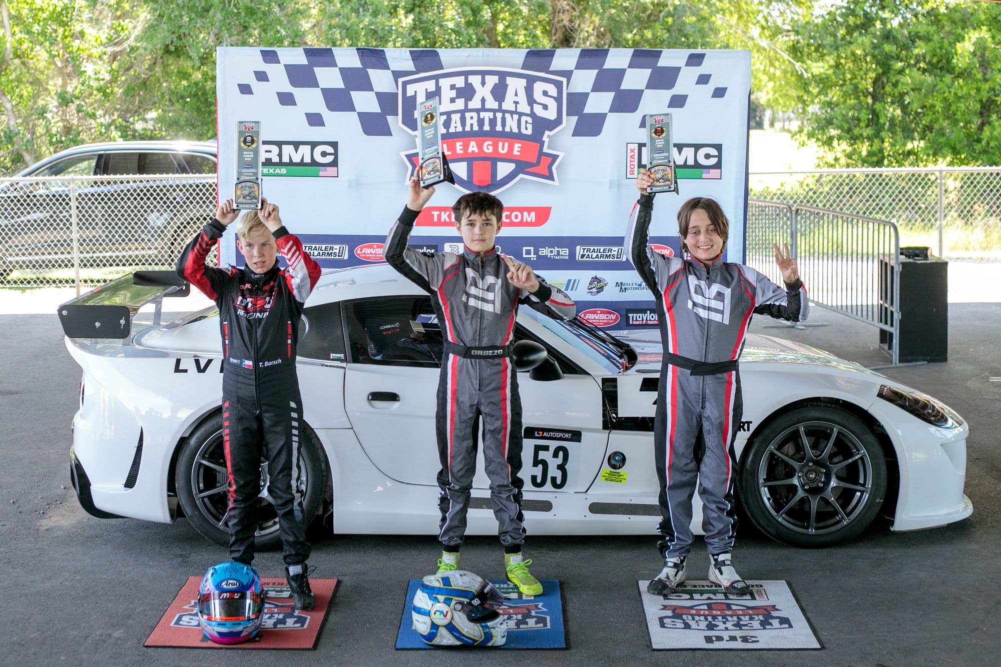 Three drivers raise trophies on the GCKI Katy podium.